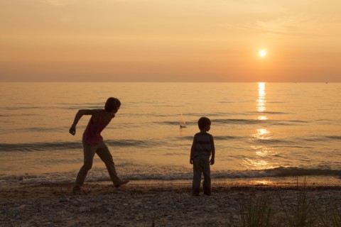 Caucasian brothers playing on beach at sunset