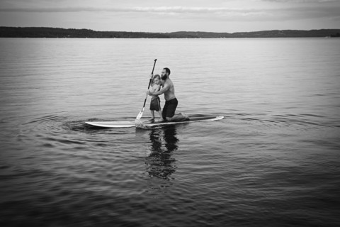 Caucasian father and son on paddleboard in lake
