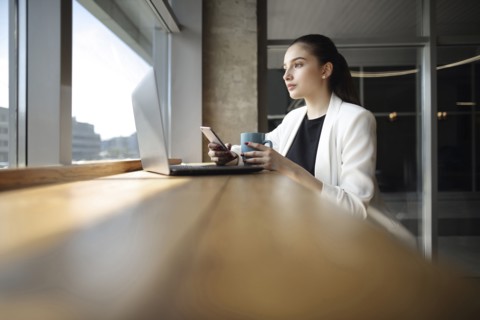 Caucasian woman drinking coffee and texting on cell phone