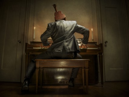 Caucasian musician with ukulele head playing piano