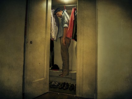 Caucasian man hanging with clothing in closet