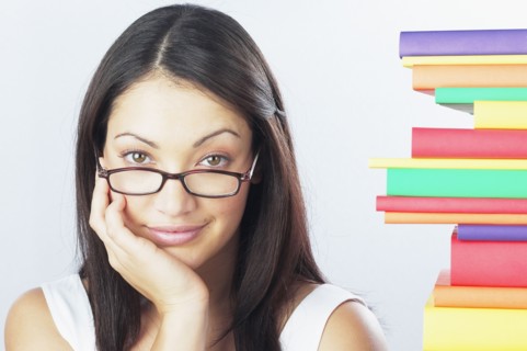 Woman wearing eyeglasses next to stack of books