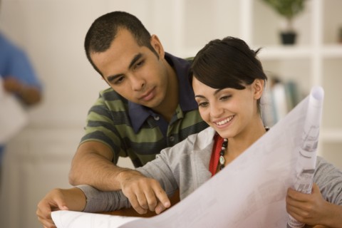 Young couple looking at blueprints in new house