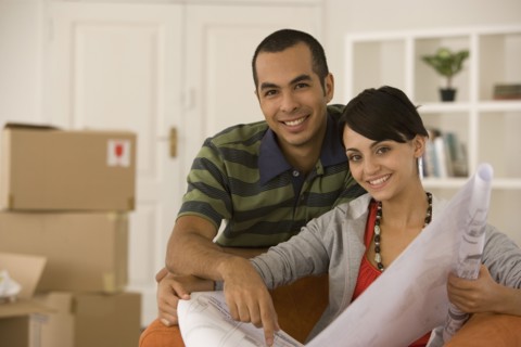 Young couple looking at blueprints in new house