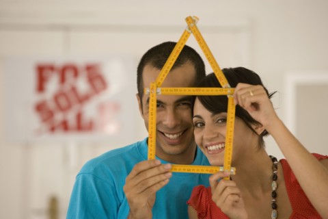 Couple holding folding ruler shaped like house