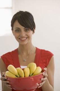 Young woman holding bowl of bananas