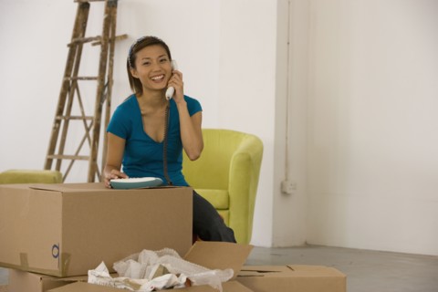 Asian woman talking on telephone in new house
