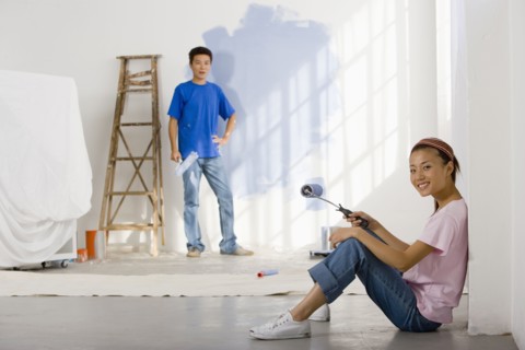Asian couple painting interior of house