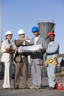 Multi-ethnic businesspeople and construction workers looking at blueprints