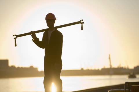 Asian male dock worker holding pipe