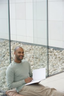 African man writing in notepad