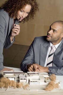 African businesspeople looking at architect's model