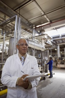 African scientist standing in factory with clipboard