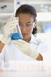 African scientist holding beaker of liquid in laboratory