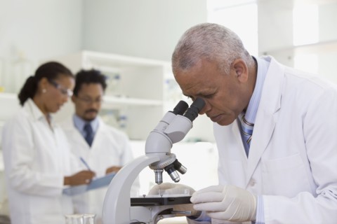 African scientist performing analysis in laboratory with microscope
