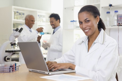 African scientist typing on laptop in laboratory