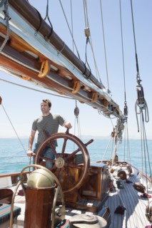 Caucasian man steering sailboat