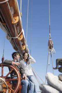 Caucasian couple at helm of sailboat