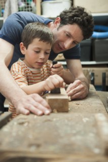 Caucasian father and son working in woodshop