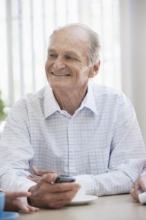 Senior Caucasian man using cell phone in cafe