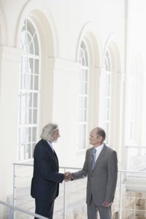 Senior Caucasian businessmen shaking hands on balcony