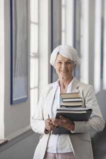 Senior Caucasian businesswoman carrying books in office