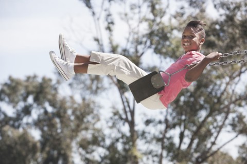African American girl playing on swing