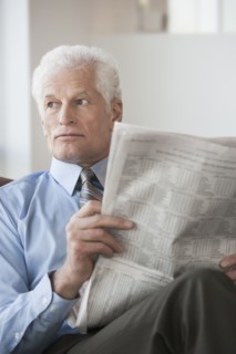 Caucasian businessman reading newspaper in office