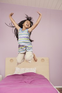 Chinese girl jumping on bed