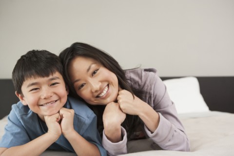 Asian mother and son laying on bed