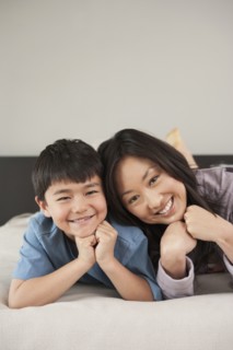 Asian mother and son laying on bed