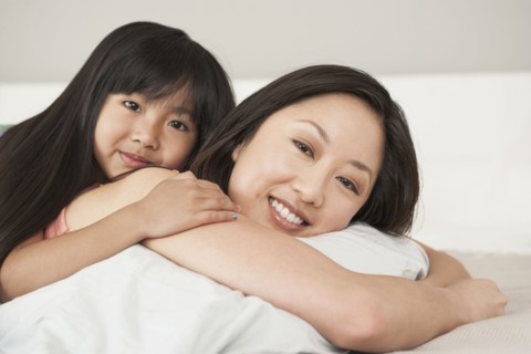 Mother and daughter laying on bed