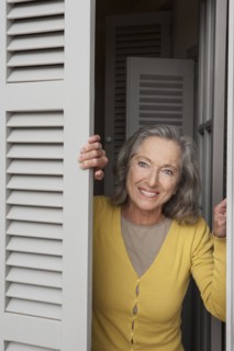 Woman peering out window shutters