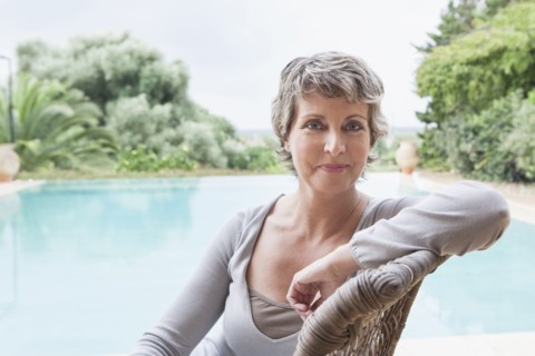 Woman smiling in armchair by swimming pool