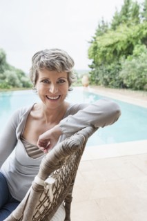 Woman smiling in armchair by swimming pool