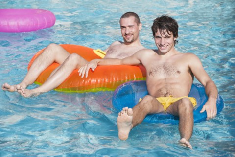 Men floating in inner tubes in swimming pool