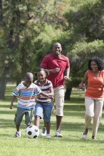 Family playing soccer in park
