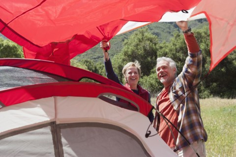 Senior Caucasian couple pitching tent in field