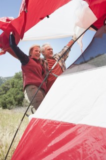 Senior Caucasian couple pitching tent in field