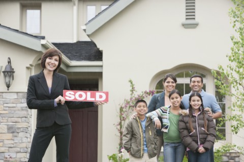 Realtor and family smiling outside new home