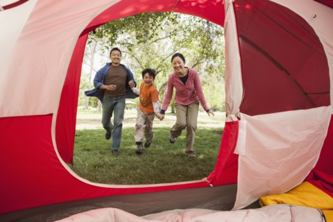 Asian family running to tent at campsite