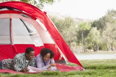 Couple reading newspaper together in tent