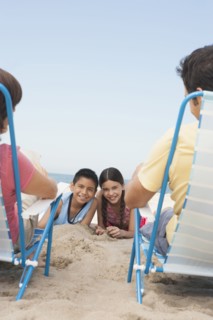 Parents watching children from lawn chairs on beach