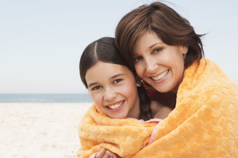 Mother and daughter wrapped in towel on beach