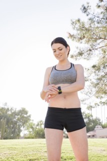 Caucasian woman standing in grass checking the time on wristwatch