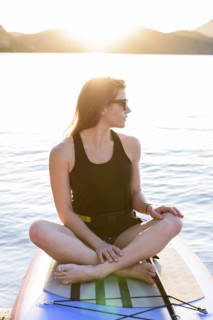 Caucasian woman sitting on paddleboard in river