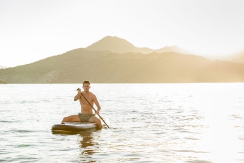 Caucasian man sitting on paddleboard in river