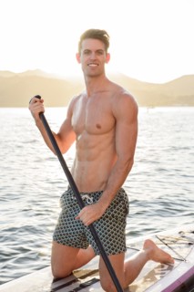 Caucasian man kneeling on paddleboard in river