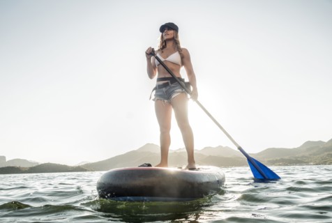 Hispanic woman standing on paddleboard in river