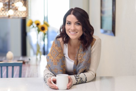 Caucasian woman leaning on counter drinking coffee